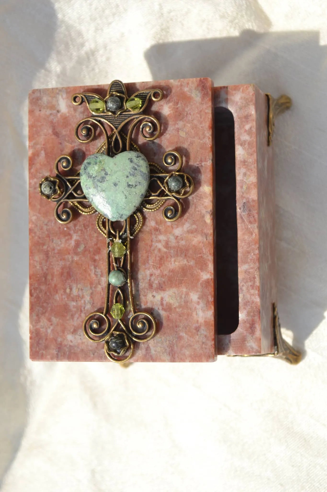 Handcrafted pink soapstone box with ornate jeweled cross and green heart gemstone lid