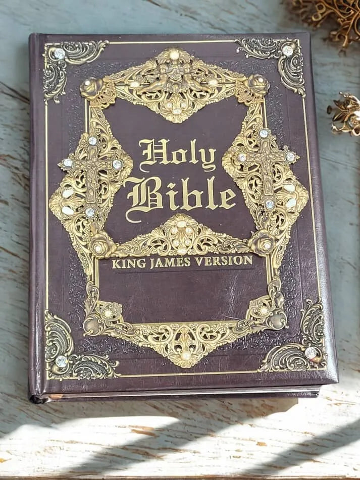 Jeweled King James Version Holy Bible with ornate gold and gemstone detailing on a wooden desk