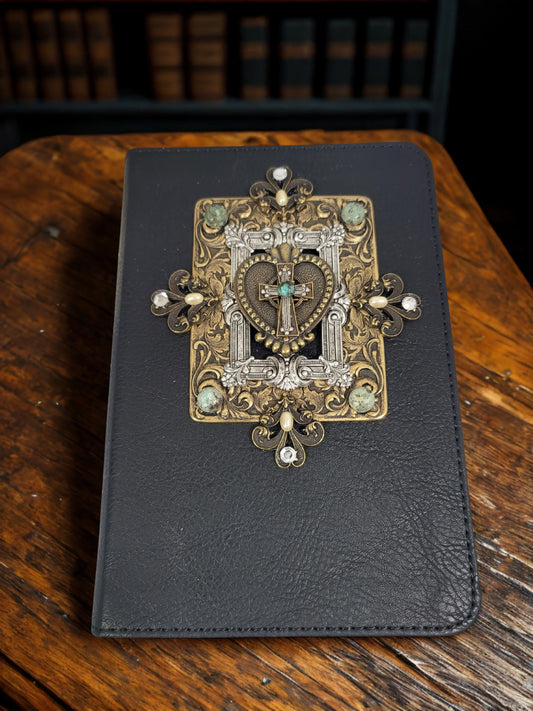 Handcrafted jeweled Bible on wooden desk, ornate silver and gold heart cross design