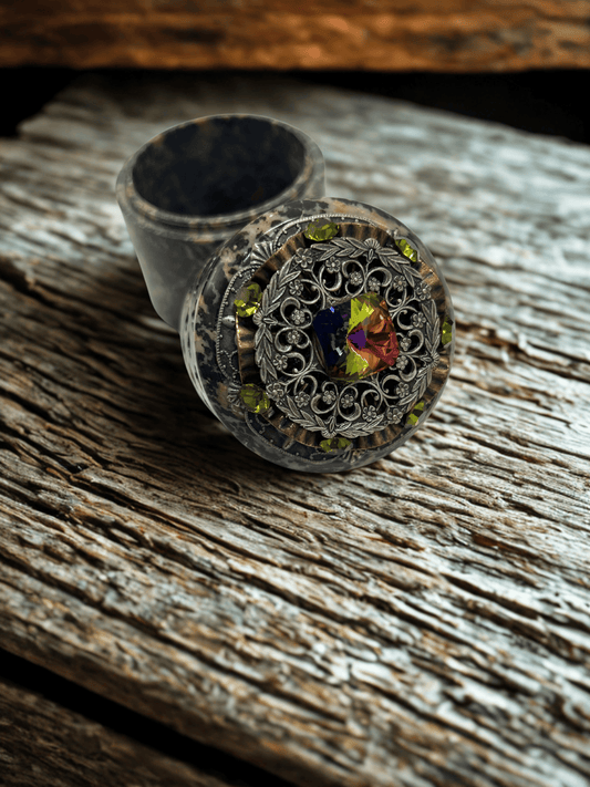 Dacole Designs handcrafted soapstone keepsake box with ornate metal filigree and colorful gem on rustic wooden surface