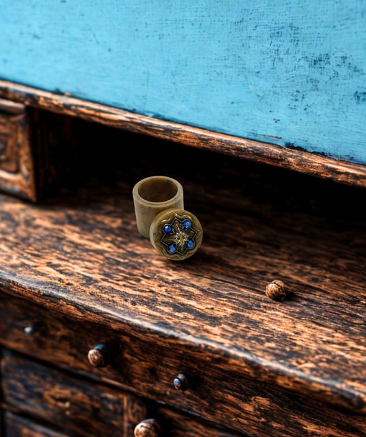 Jo Marz jeweled fleur de lis trinket box with blue stones on wooden surface and blue background