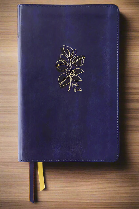 NIV Women's Devotional Bible leather navy with gold leaf design and ribbon markers on wooden surface