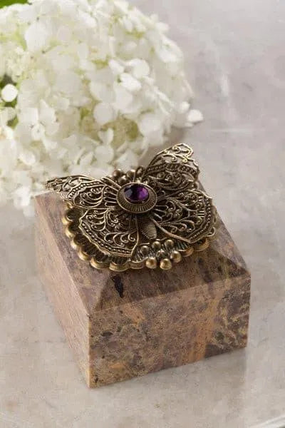 Jeweled butterfly trinket box with ornate metal butterfly and gemstone on marble base