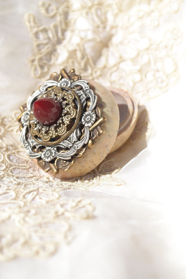 Dacole Designs jeweled soapstone keepsake box with ornate metalwork and red gemstone on lace background