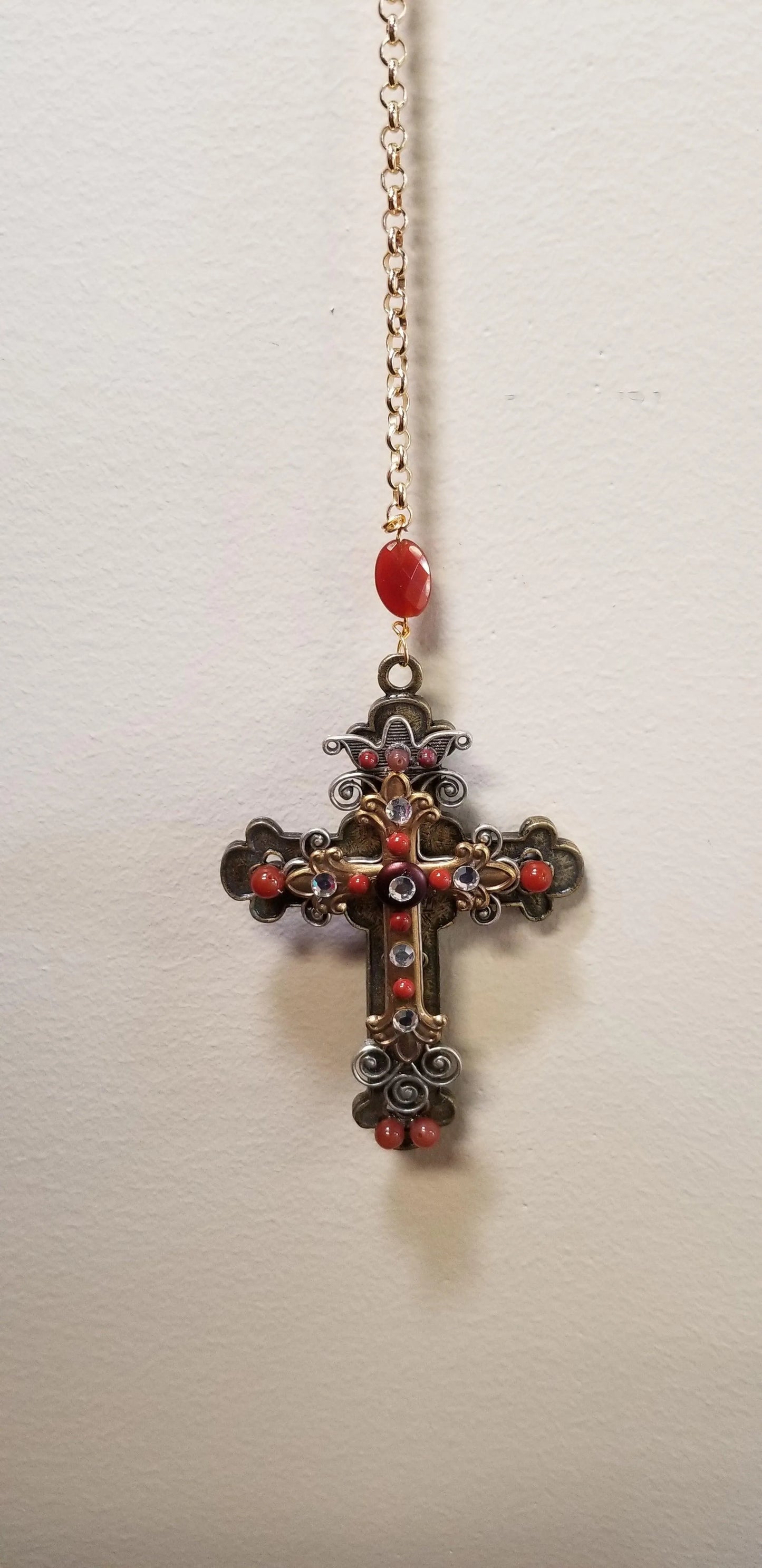 Jo Marz limited edition faith cross ornament with intricate design and red gemstone accents hanging by a gold chain