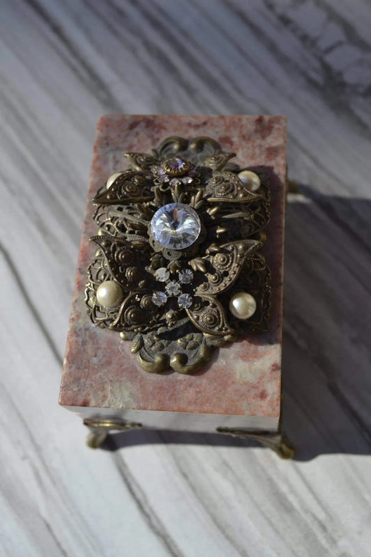 Dacole Designs jeweled soapstone butterfly box with ornate metalwork and gemstone accents on a pink stone surface